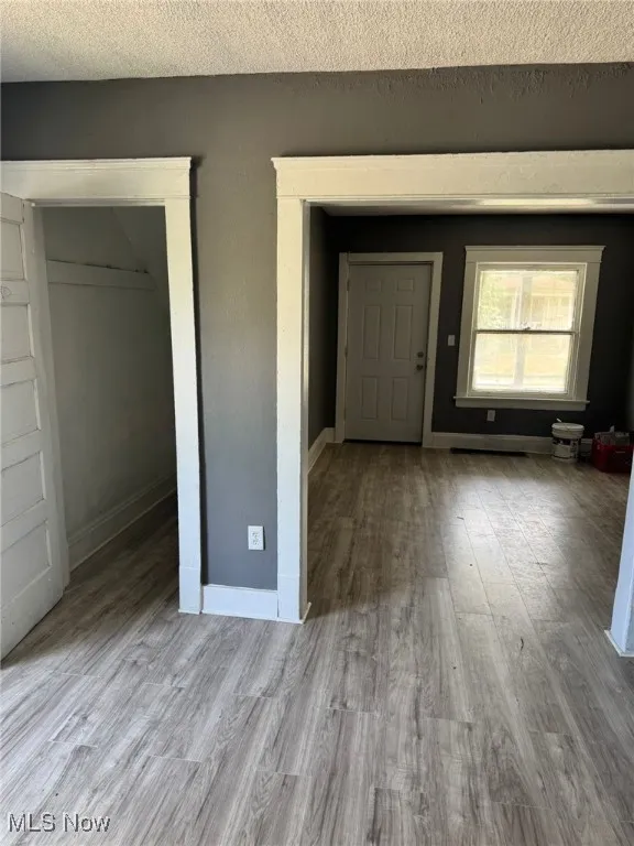 Entryway with wood finished floors, a textured ceiling, and baseboards