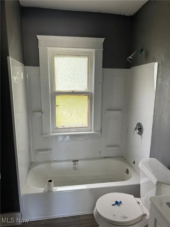 Full bathroom featuring toilet, shower / washtub combination, wood finished floors, and vanity