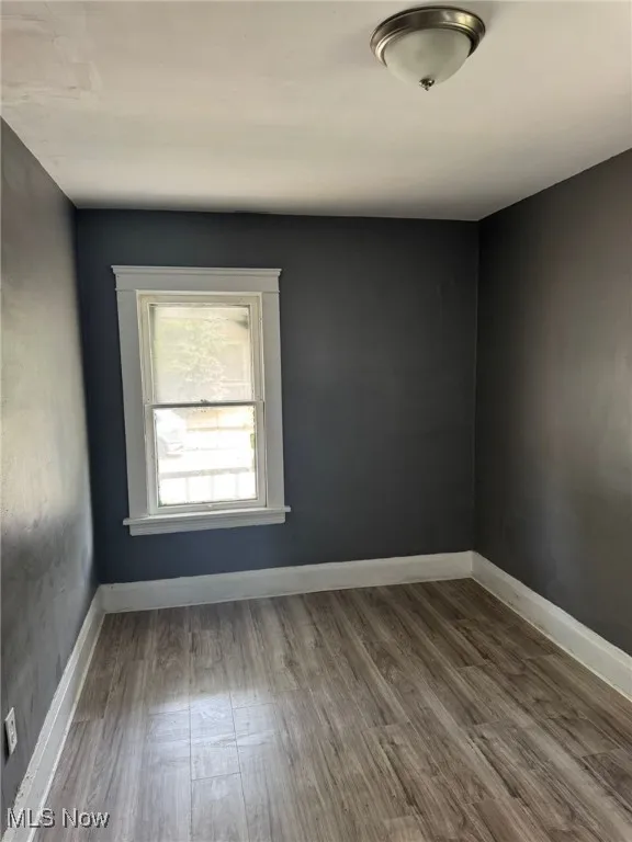 Unfurnished room featuring wood finished floors and baseboards