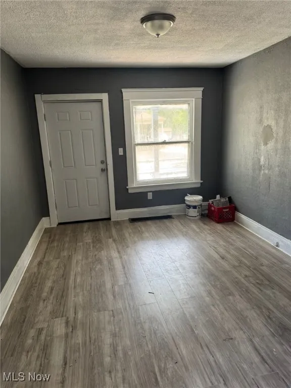Foyer entrance with wood finished floors, a textured ceiling, and baseboards