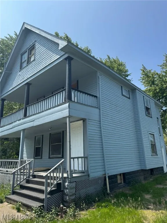 View of side of home featuring a balcony and covered porch