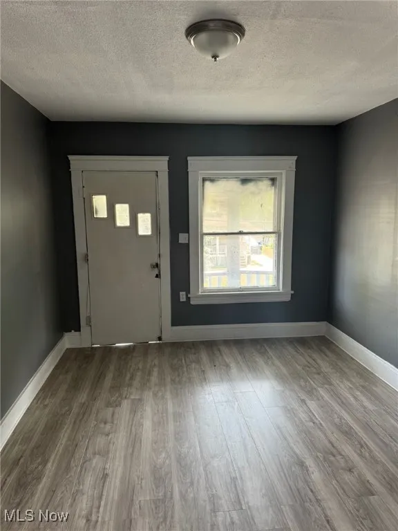 Entryway featuring wood finished floors, a textured ceiling, and baseboards