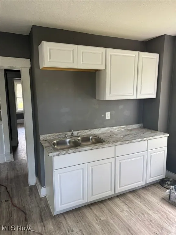 Kitchen featuring a sink, white cabinets, and light wood finished floors