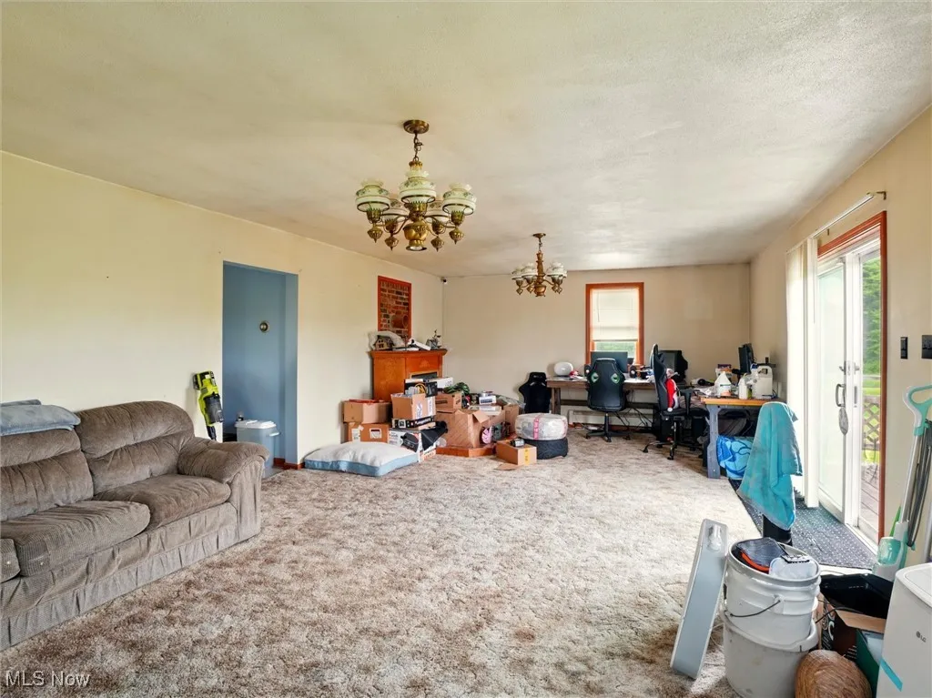Living room featuring a chandelier, an office area, and carpet