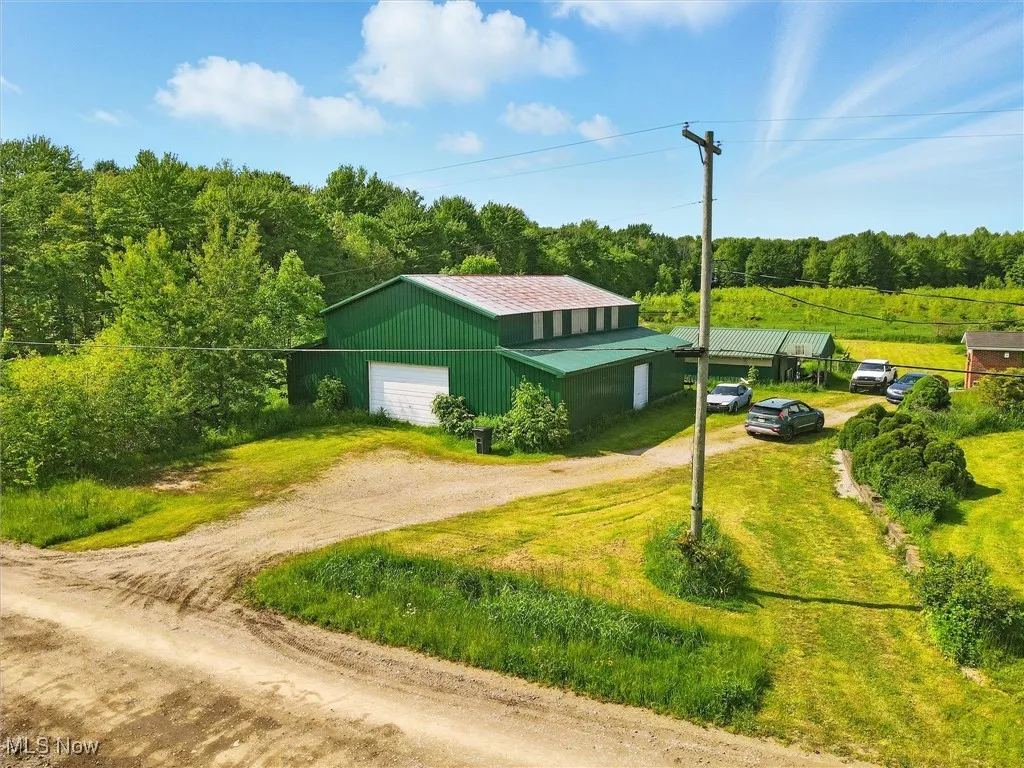 View of side of property featuring driveway, an outbuilding, and a forest view