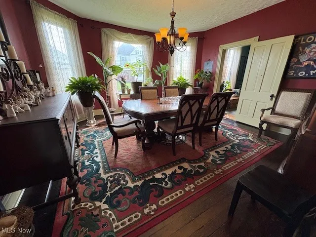 Dining room featuring a chandelier, wood-type flooring, and a textured ceiling