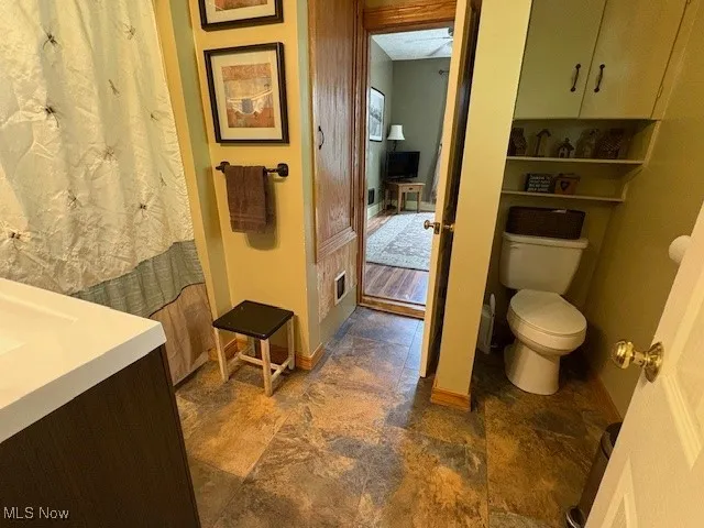Bathroom featuring toilet, vanity, and stone finish flooring