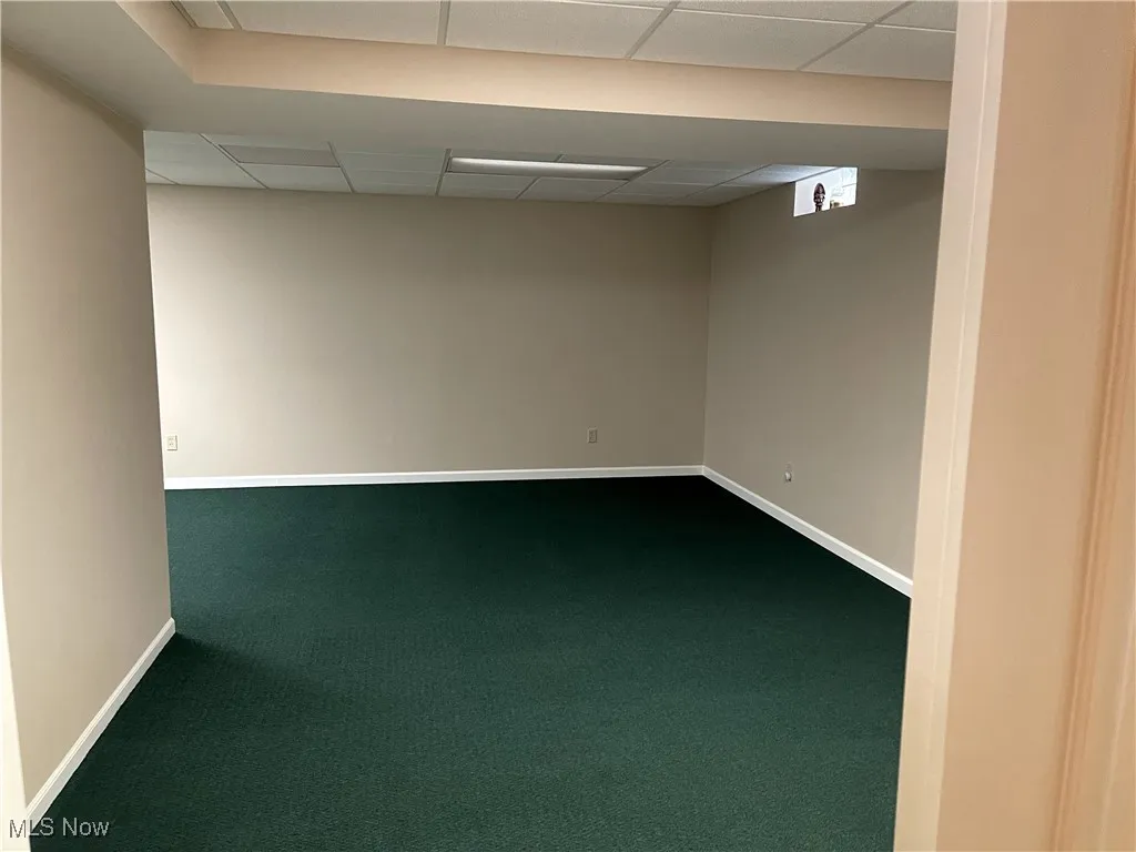 Finished below grade area with dark carpet, baseboards, and a drop ceiling