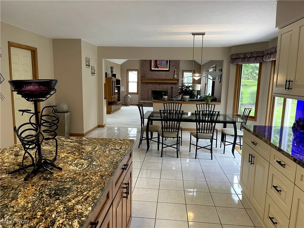 Dining space with a fireplace, light tile patterned flooring, and baseboards