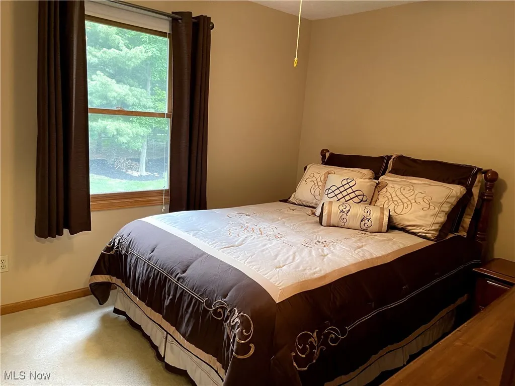 Carpeted bedroom featuring multiple windows and baseboards