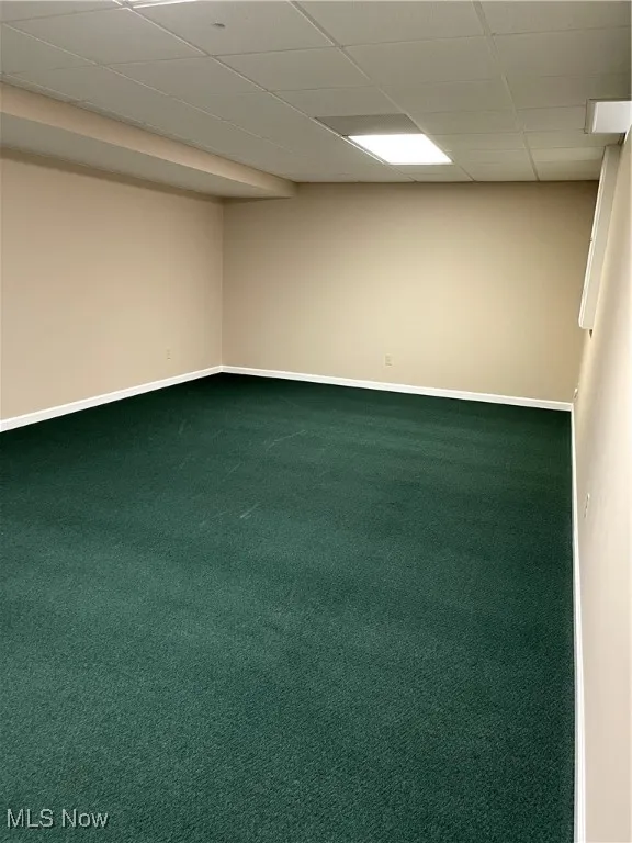 Empty room featuring baseboards, carpet flooring, and a paneled ceiling