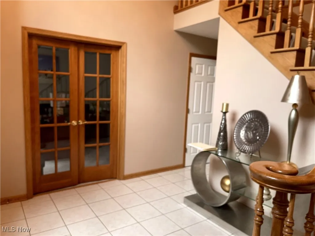 Workout area with french doors, baseboards, and light tile patterned floors