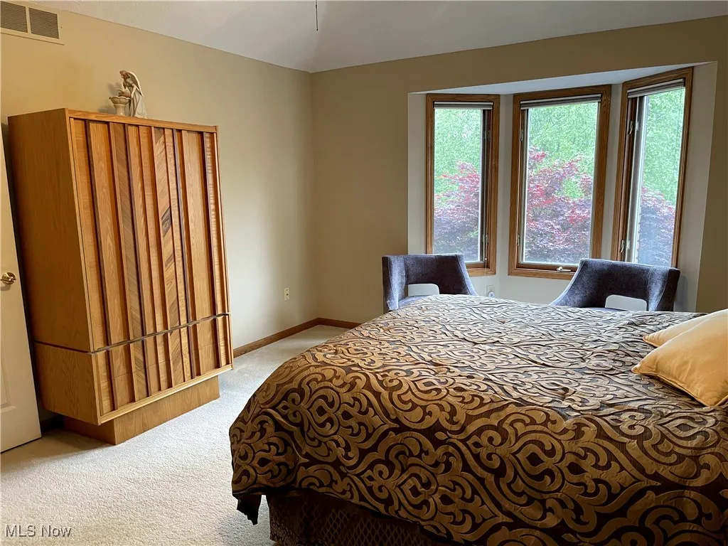Bedroom featuring carpet flooring, multiple windows, baseboards, and vaulted ceiling