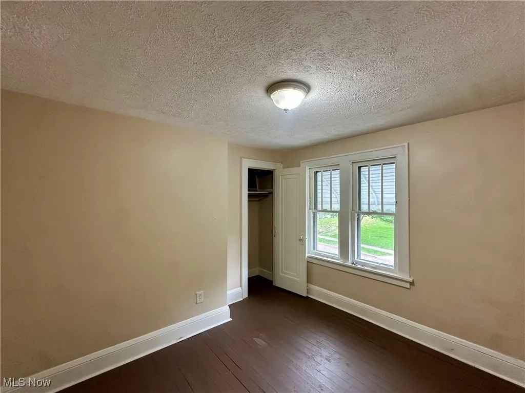 Unfurnished bedroom with baseboards, dark wood finished floors, a closet, and a textured ceiling