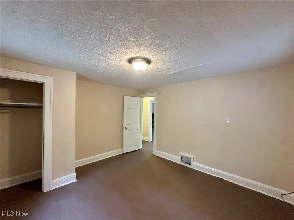 Unfurnished bedroom with baseboards, a textured ceiling, and a closet