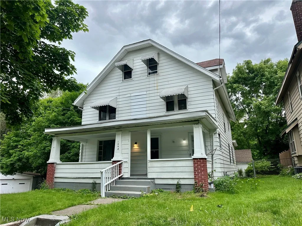 American foursquare style home featuring covered porch and a front yard
