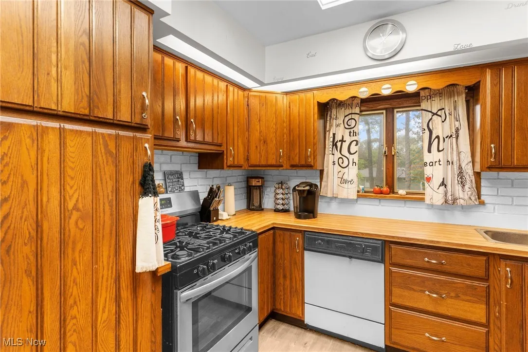 Kitchen with dishwasher, stainless steel gas range oven, and brown cabinets