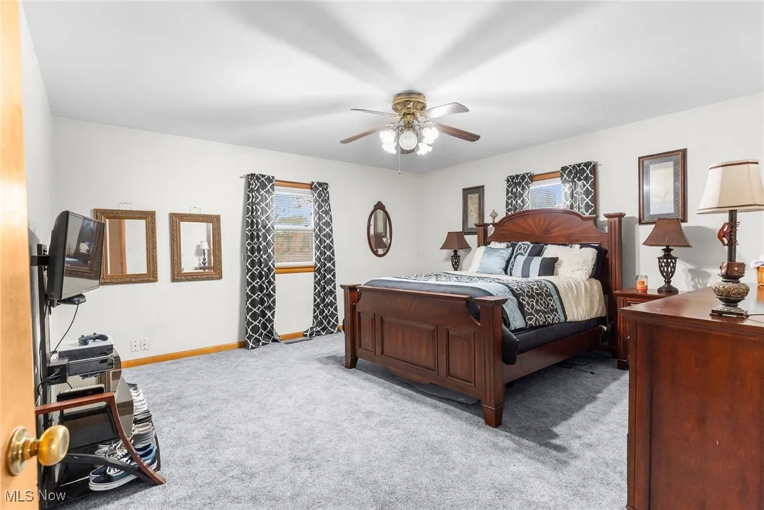Carpeted bedroom featuring baseboards and ceiling fan