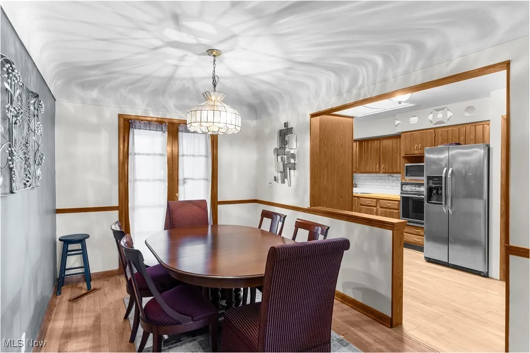 Dining room with light wood-type flooring, a chandelier, and baseboards