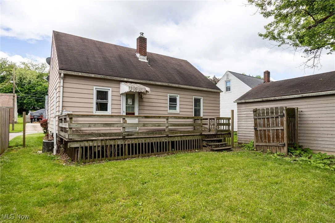 Rear view of property featuring a deck, a chimney, a yard, and central AC unit