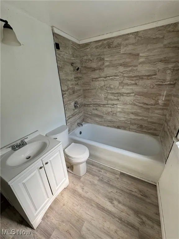 Full bathroom with toilet, vanity, shower / bath combination, and wood finished floors