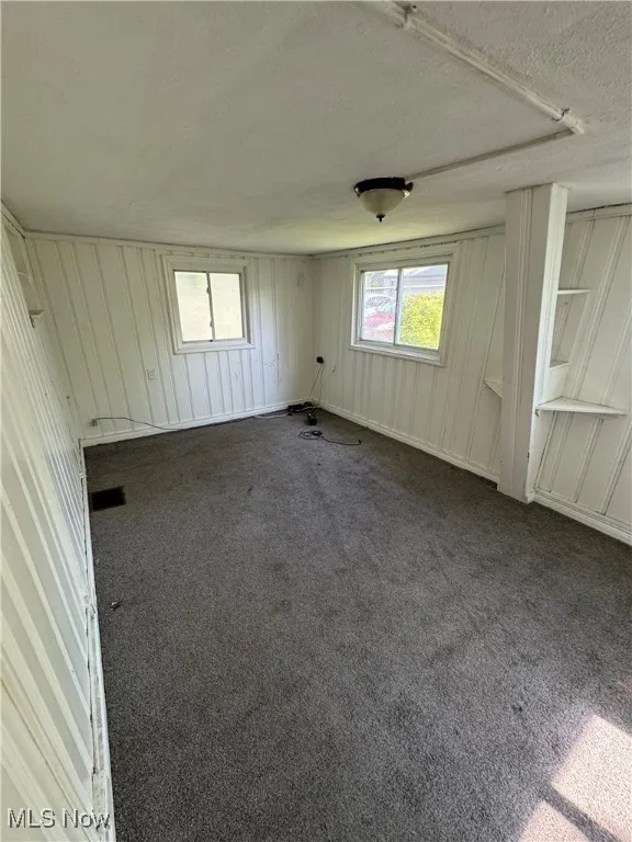 Unfurnished room with dark colored carpet and a textured ceiling