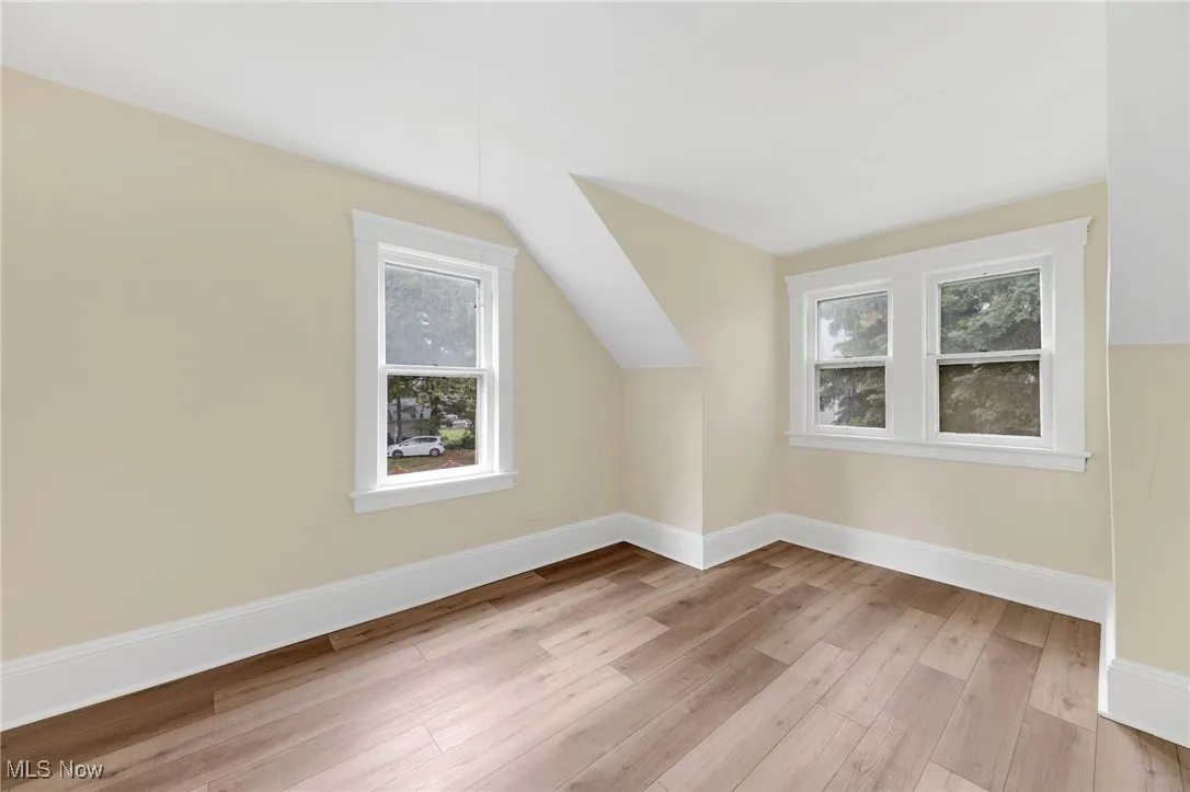 Additional living space with wood finished floors, baseboards, and vaulted ceiling