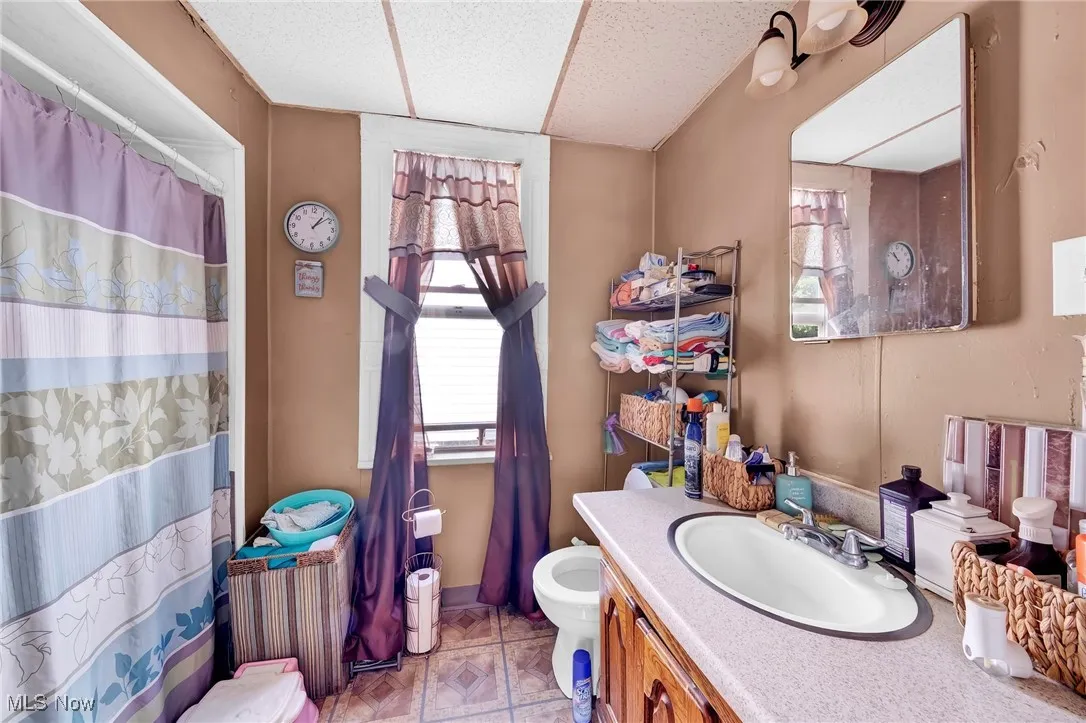 Bathroom featuring toilet, vanity, baseboards, and curtained shower