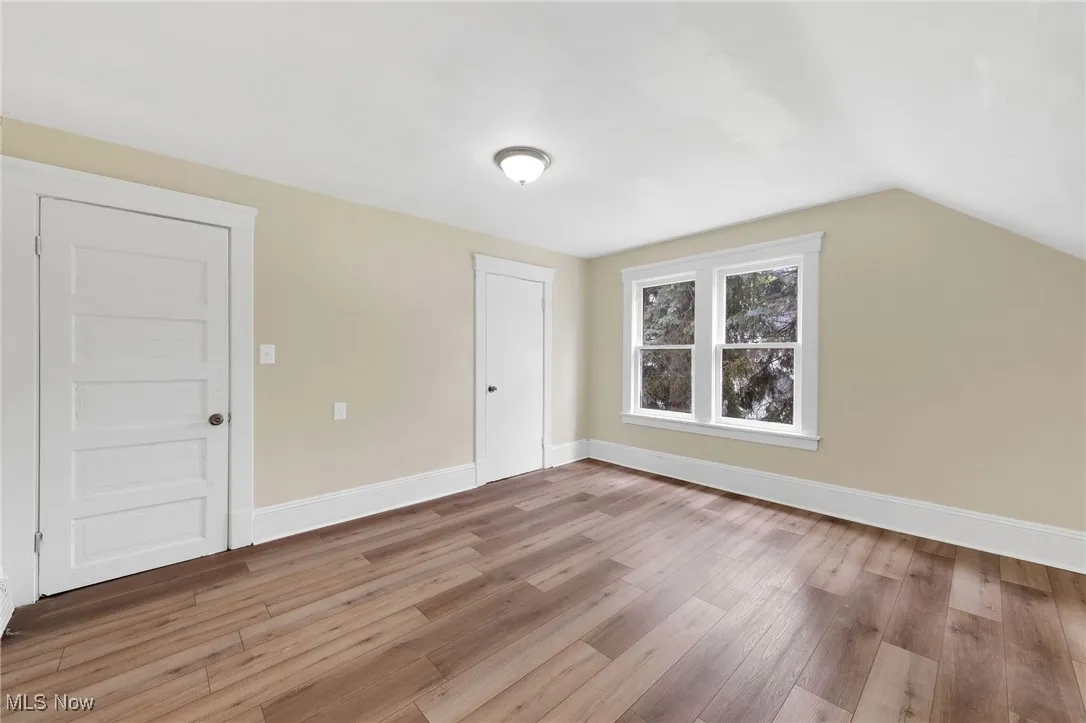Bonus room with wood finished floors, vaulted ceiling, and baseboards