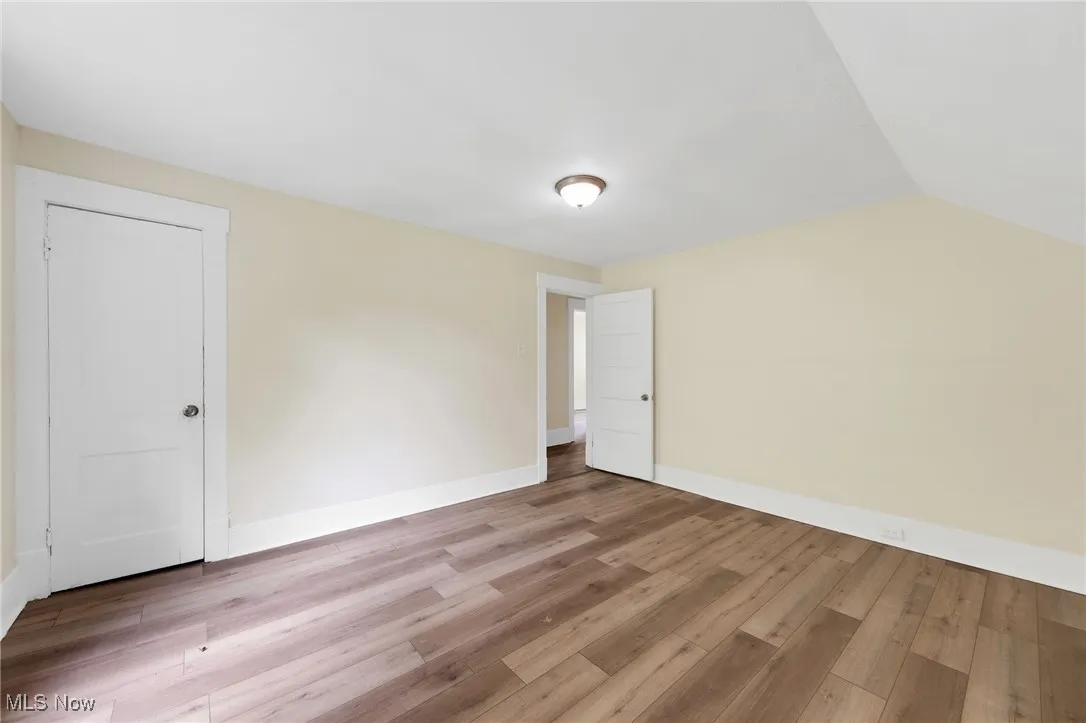 Additional living space featuring light wood-style flooring, baseboards, and lofted ceiling