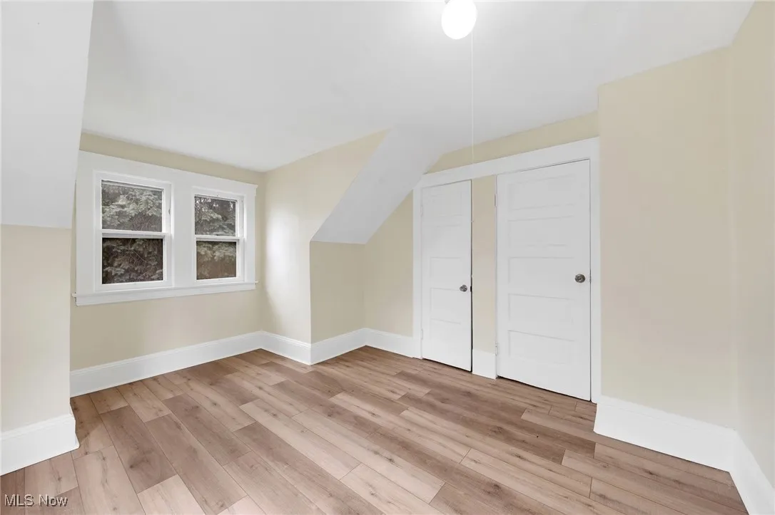 Bonus room featuring light wood finished floors, baseboards, and vaulted ceiling