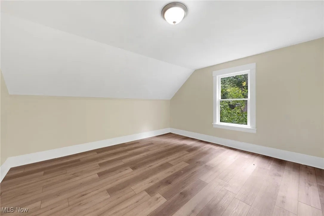 Bonus room featuring vaulted ceiling, baseboards, and wood finished floors