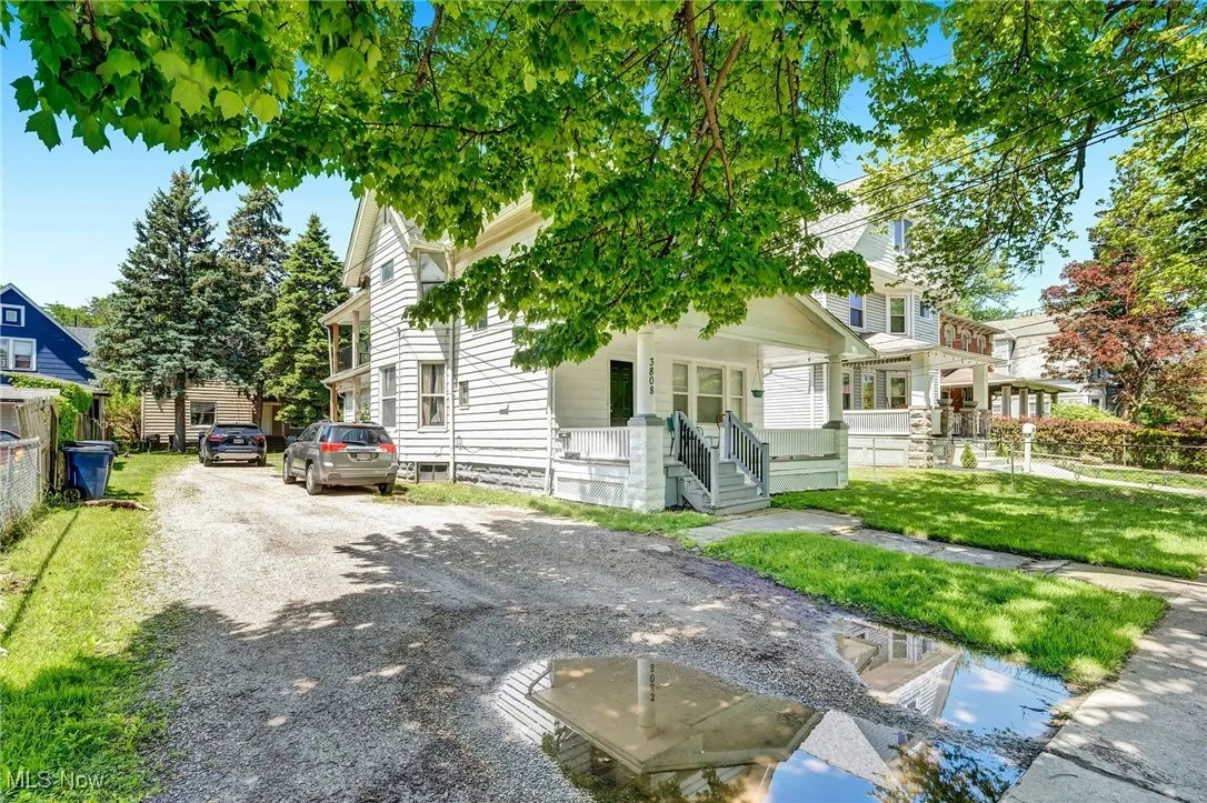 View of front of property with covered porch, a front lawn, and gravel driveway