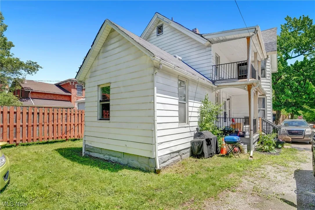 View of side of property with a balcony and a shingled roof
