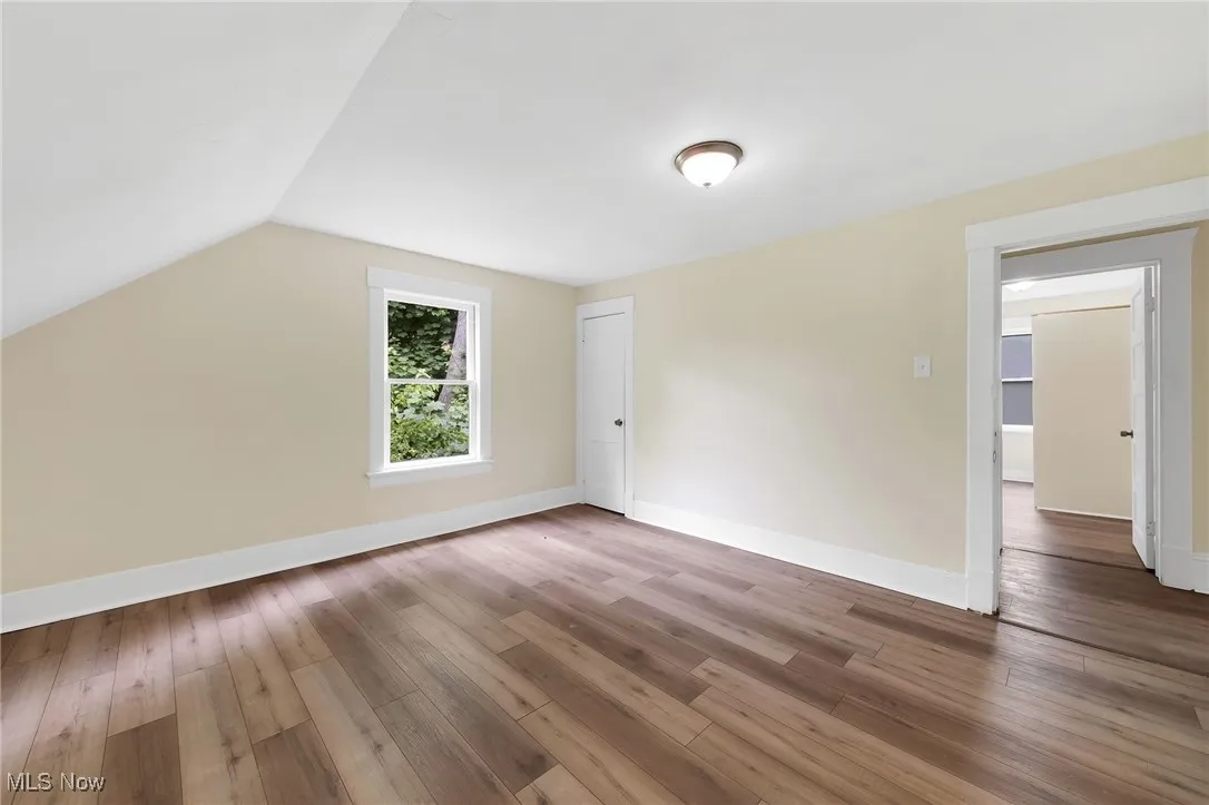 Additional living space featuring hardwood / wood-style floors, vaulted ceiling, and baseboards