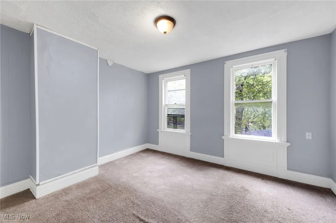 Carpeted empty room with baseboards and a textured ceiling