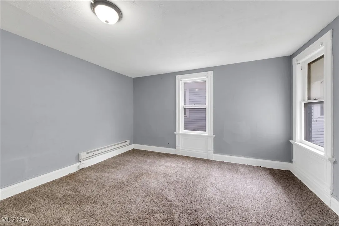Carpeted empty room featuring a baseboard radiator and baseboards