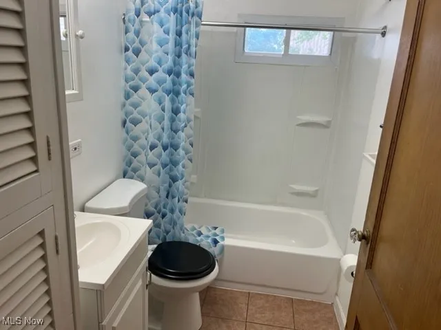 Full bathroom with shower / tub combo with curtain, vanity, tile patterned floors, and toilet