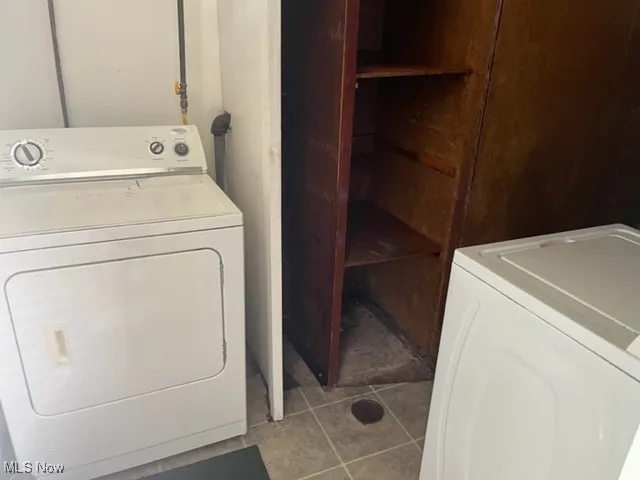 Laundry area featuring light tile patterned floors and washing machine and clothes dryer