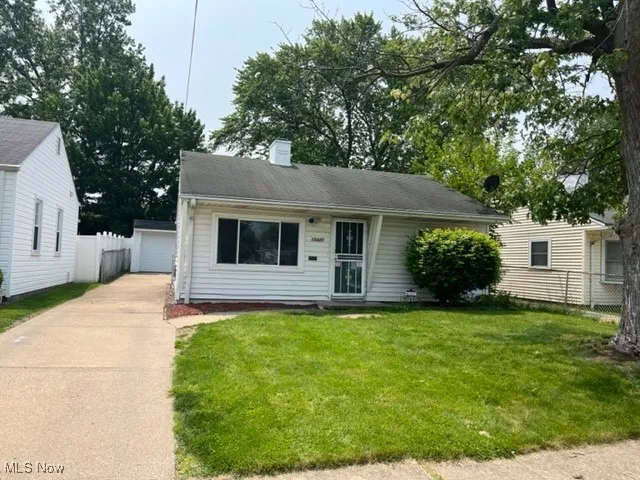 View of front of property with an outdoor structure, a chimney, and a garage