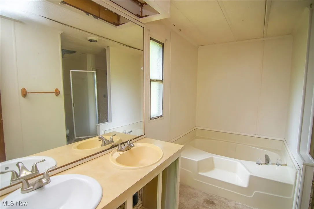 Full bathroom featuring a garden tub, double vanity, a shower with shower door, and healthy amount of natural light
