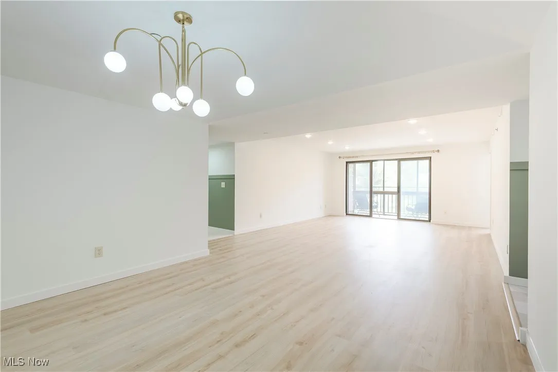 Spare room featuring a chandelier, light wood-style flooring, baseboards, and recessed lighting
