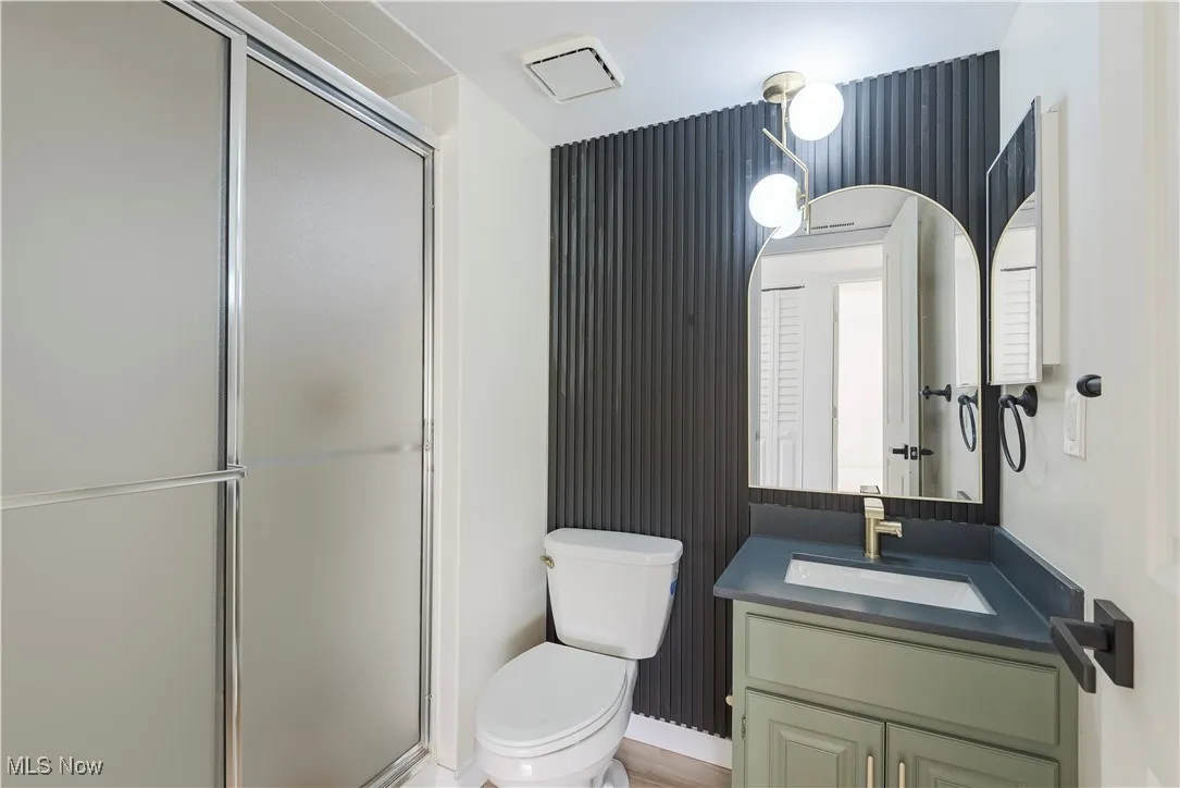Full bathroom with vanity, a shower stall, and toilet