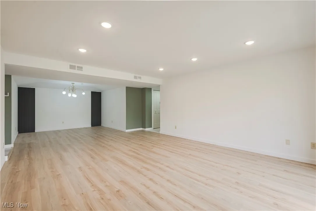 Unfurnished room with light wood finished floors, a chandelier, recessed lighting, and baseboards