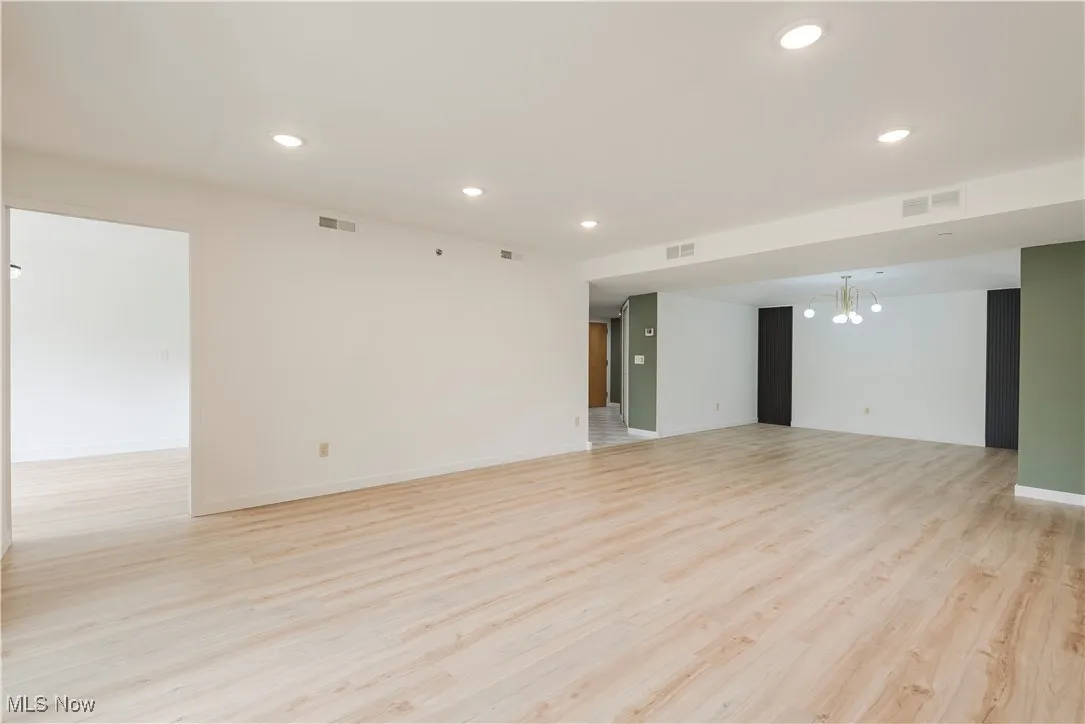 Unfurnished room featuring baseboards, recessed lighting, light wood-style flooring, and a chandelier