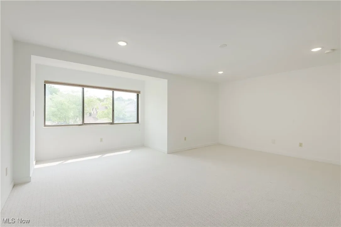 Empty room with light carpet, recessed lighting, and baseboards