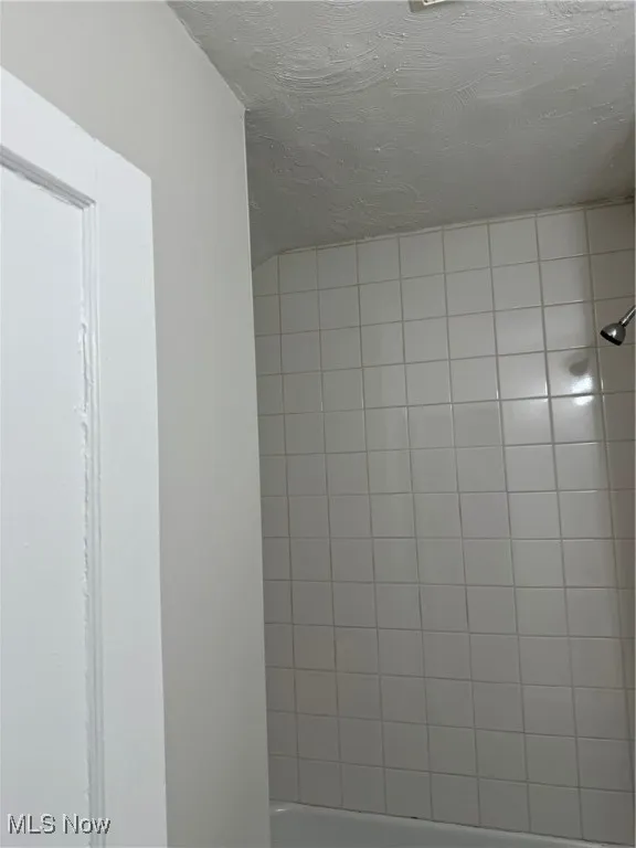 Bathroom view of tiled shower and a textured ceiling