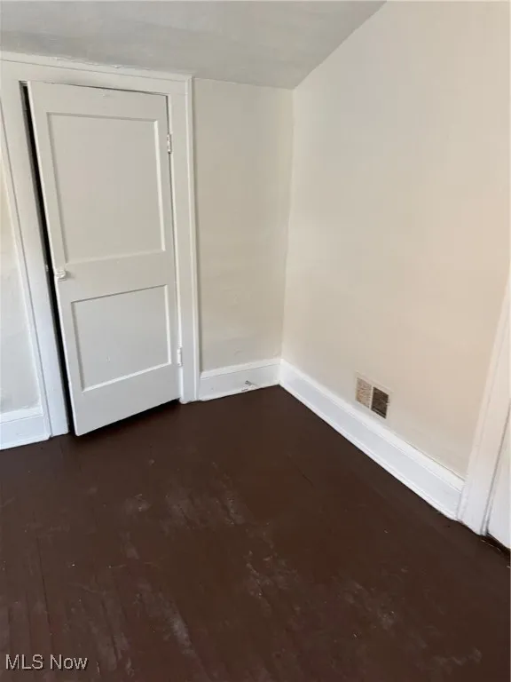 Unfurnished room with baseboards and dark wood-style floors