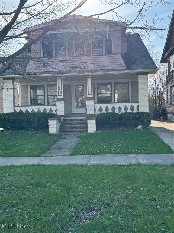 View of front of property with a front lawn, brick siding, and covered porch