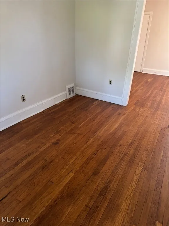 Unfurnished room featuring baseboards and dark wood-type flooring